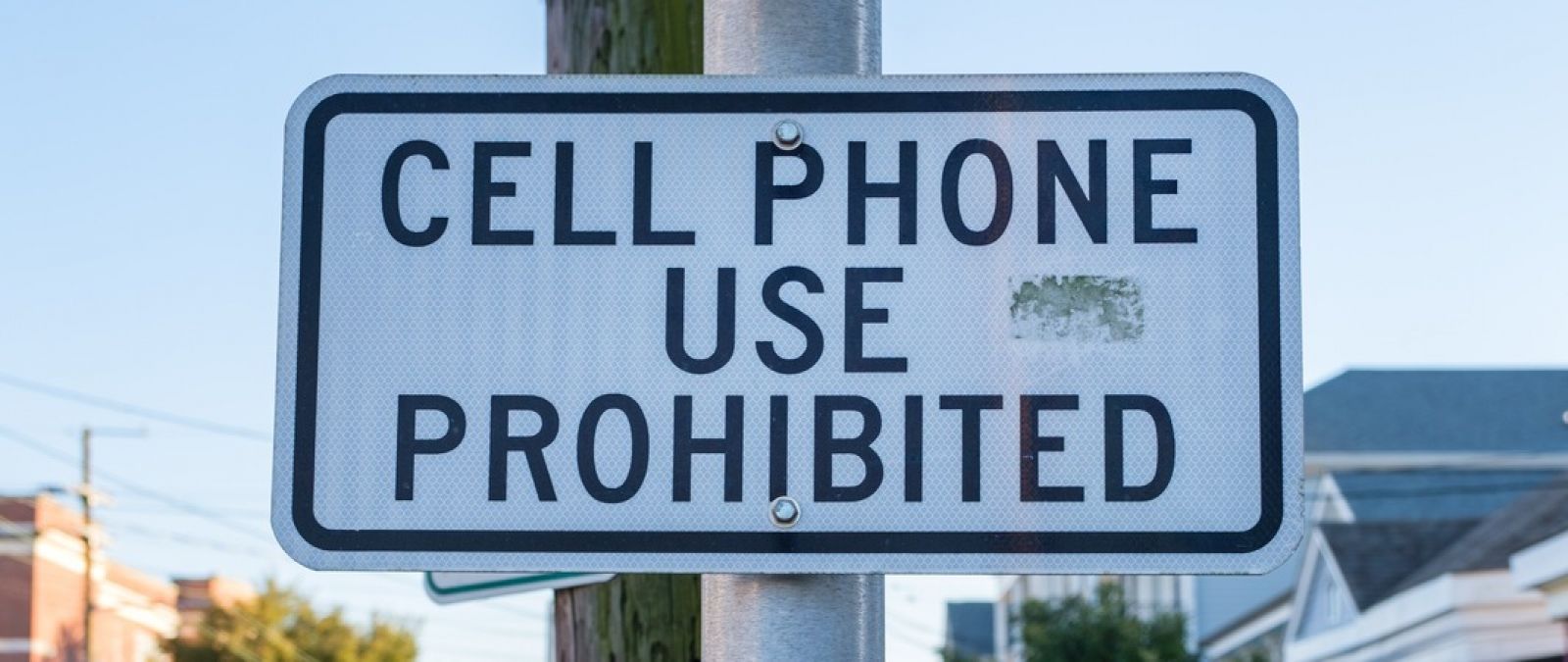 A sign on a pole that reads “cell phone use prohibited.” banner image